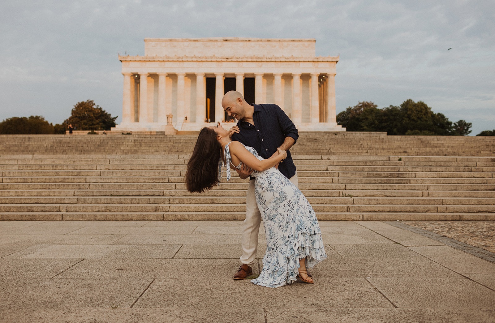 Man dips woman in front of Lincoln Memorial at sunrise