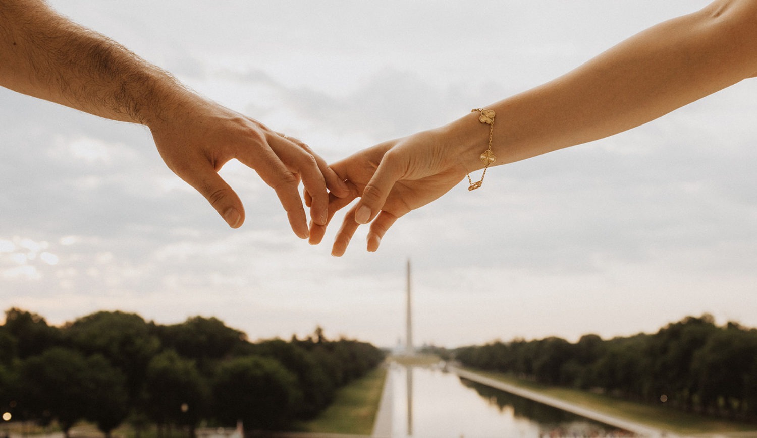 DC engagement photographer captures couple holding hands in front of Washington Monument and Reflecting Pool