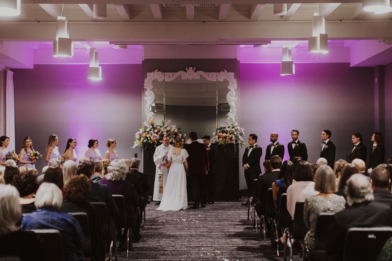 Couple exchanges vows in room with purple lighting