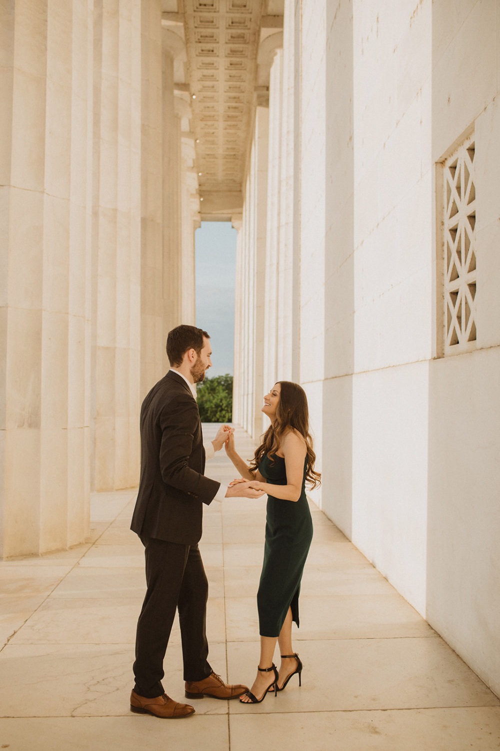 Couple dances beside columns at sunrise captured by DC engagement photographer