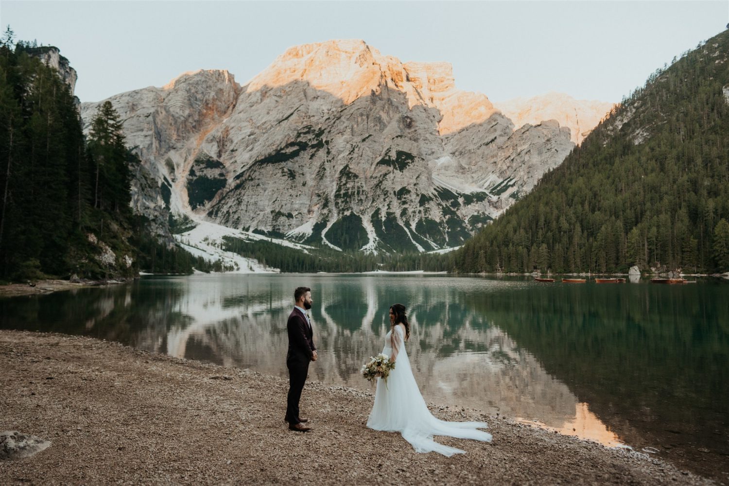 Couple faces each other by lakeside elopement in the Dolomites
