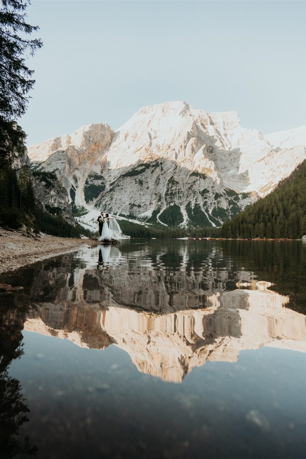 Couple embraces by lake at dolomites elopement captured by destination wedding photographer
