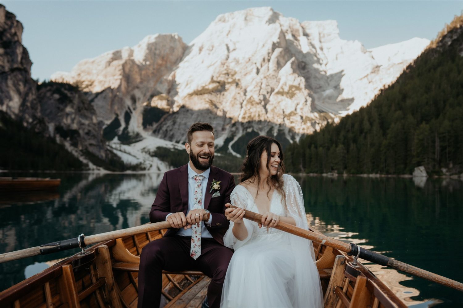 Couple rows boat on lake a Dolomites elopement captured by destination wedding photographer 