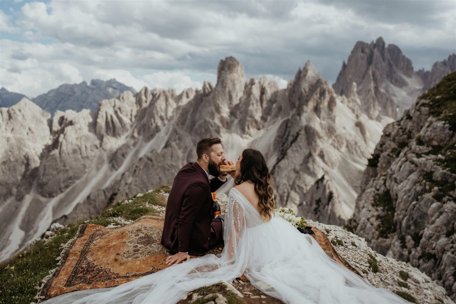 Couple eats two ends of the same piece of bread on mountaintop at Italy elopement
