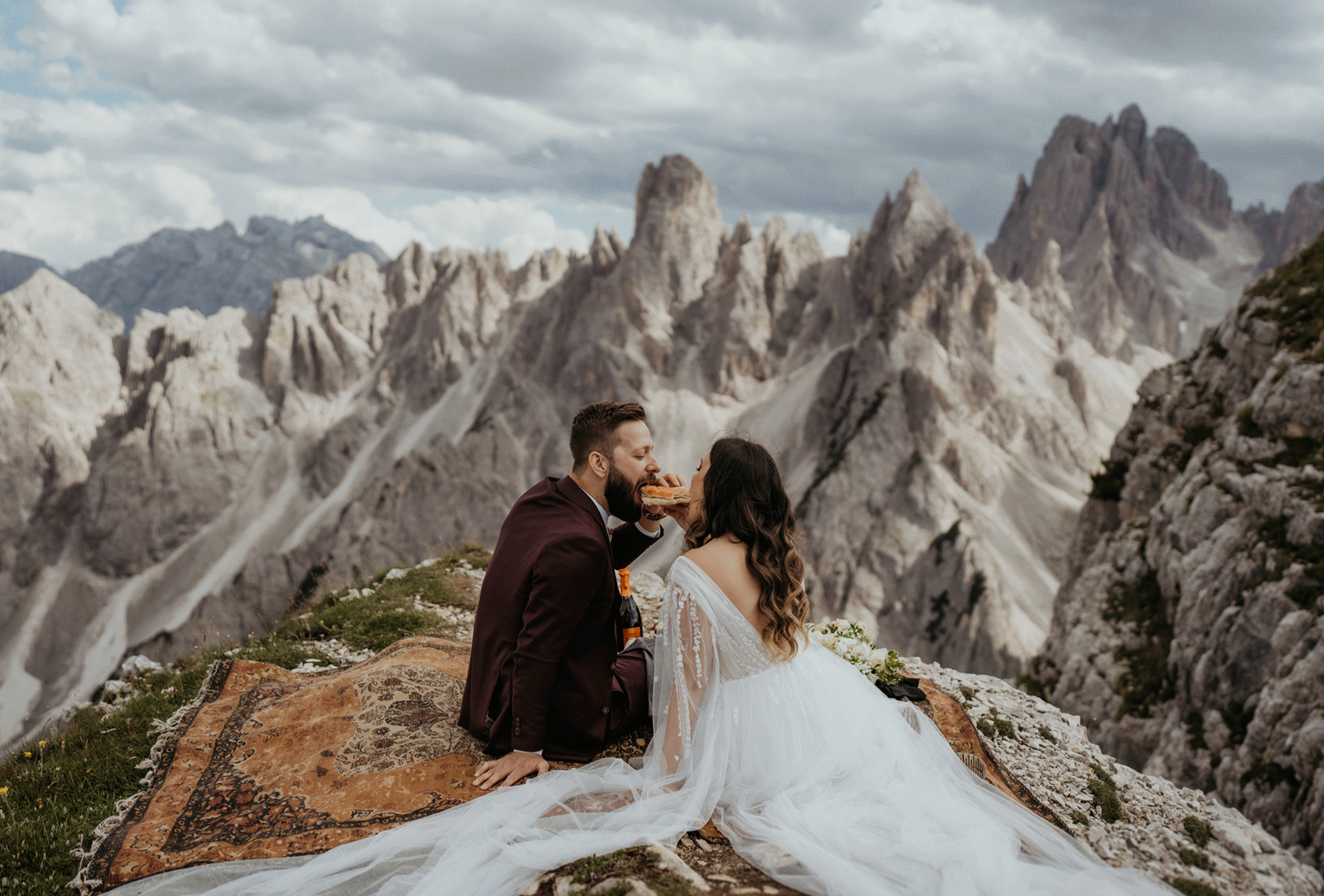 Couple eats two ends of the same piece of bread on mountaintop at Italy elopement