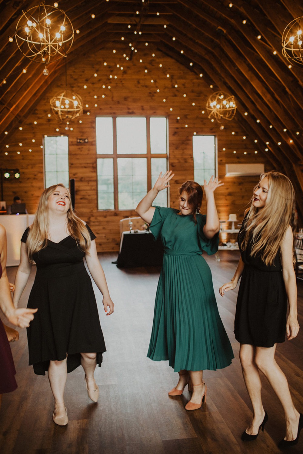 Guests dance in barn wedding reception lit by twinkle lights
