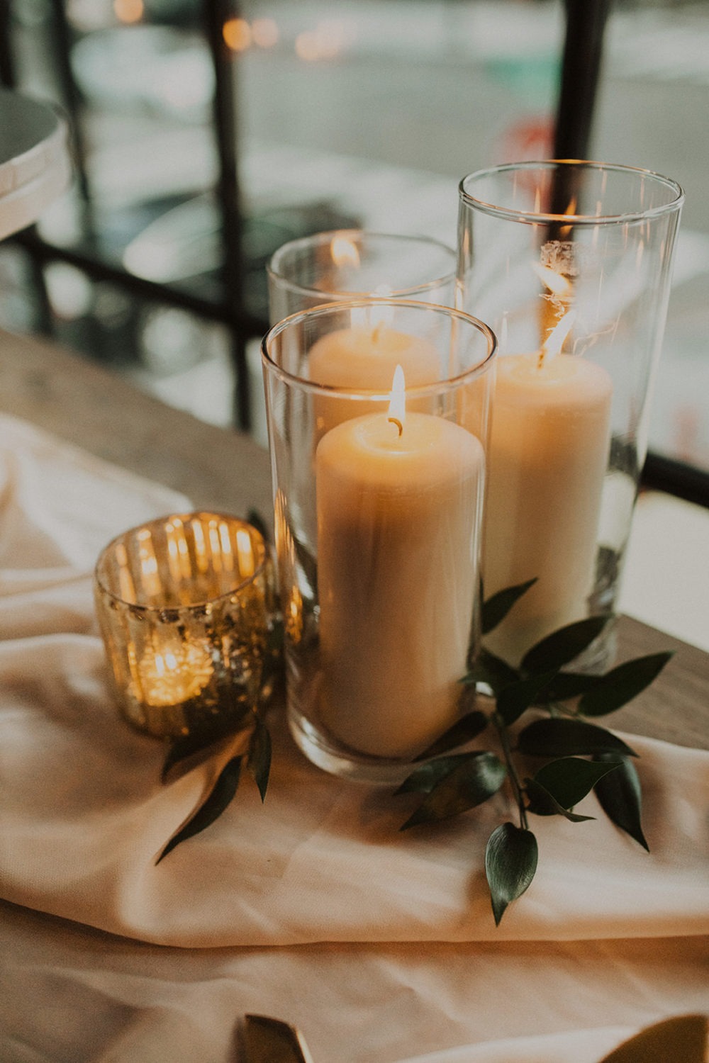 lit candles as decor with greenery on wedding reception table