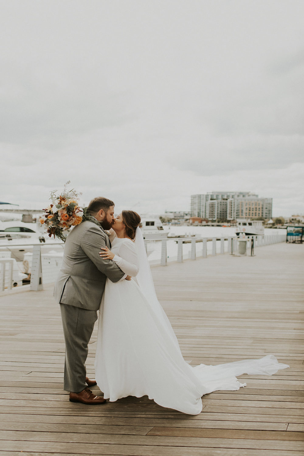 Couple kisses holding bouquet at Navy Yard DC wedding