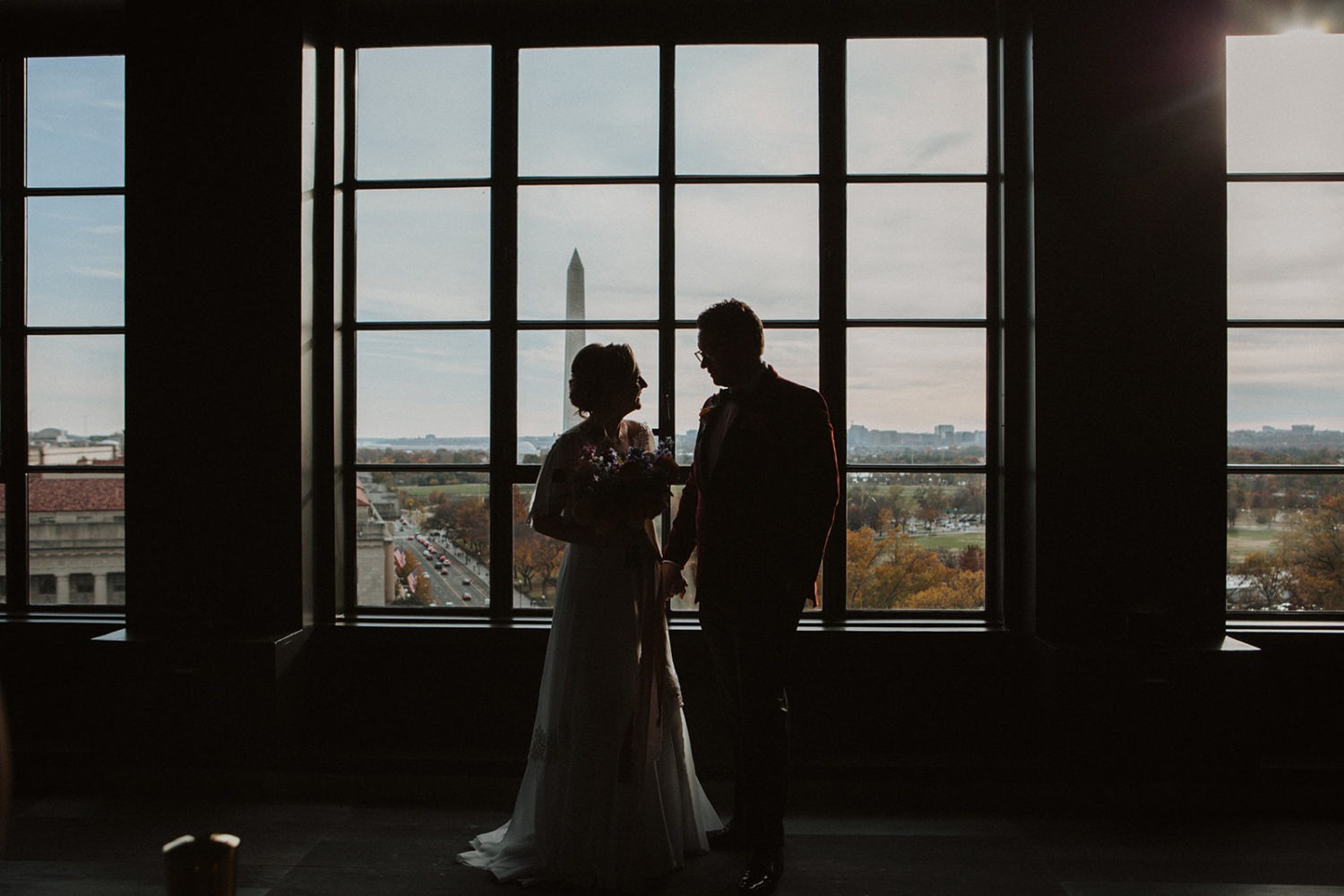 Couple stands in front of window with city views at Hotel Washington, Washington DC wedding