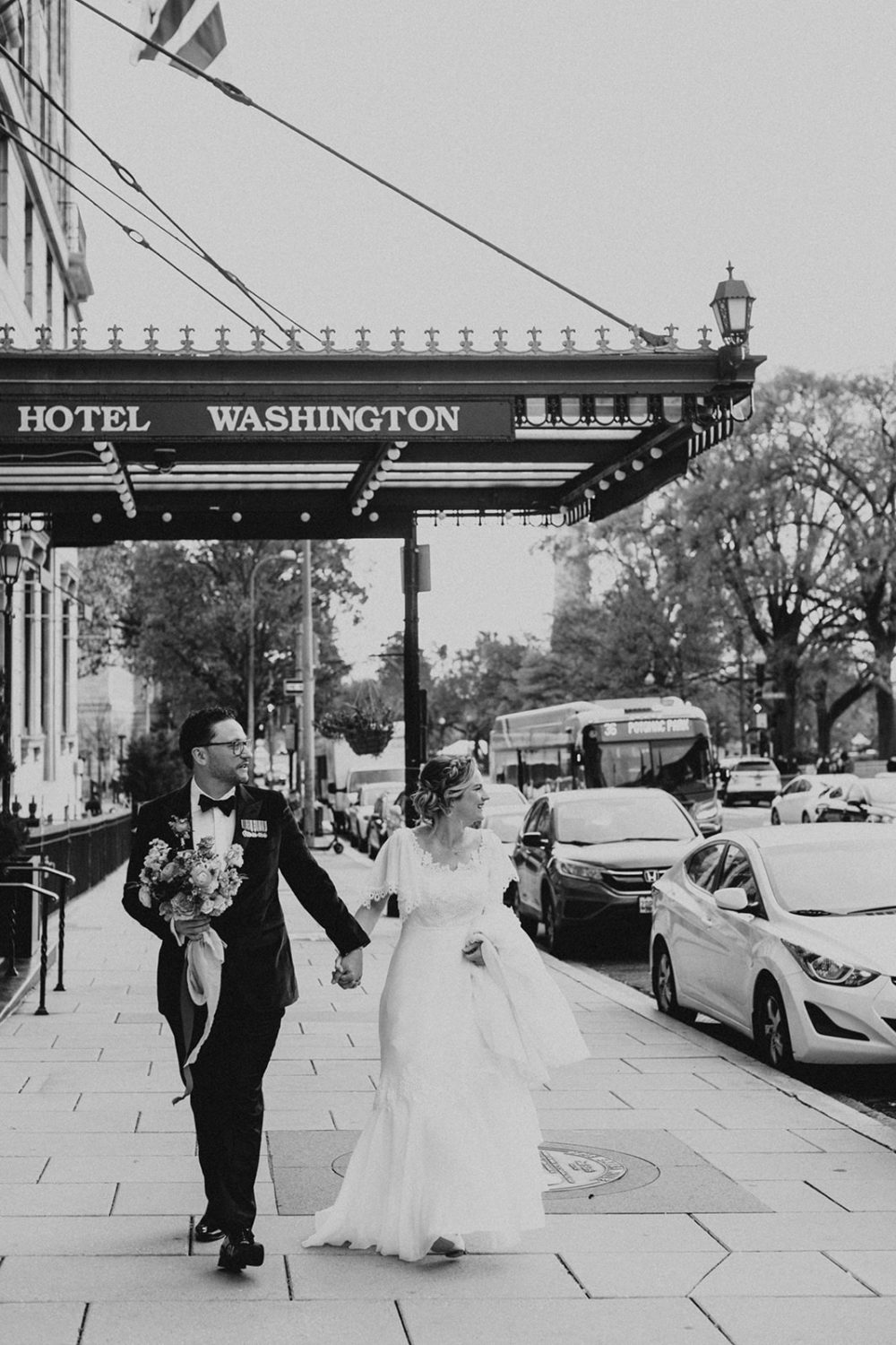 Couple walks down city street under  Hotel Washington, Washington DC sign