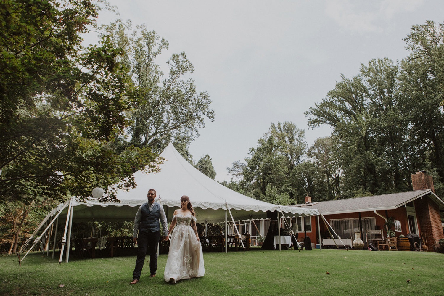 Couple walks by backyard wedding tent