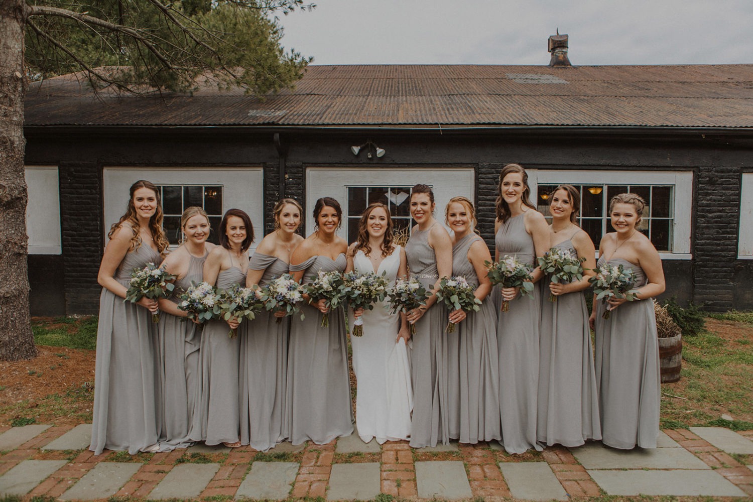 Bridesmaids stand with bride in a row holding wedding bouquets