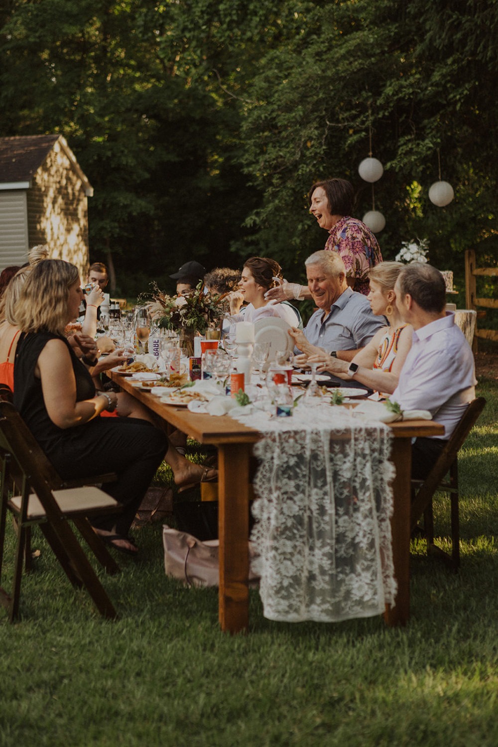 Guests sit at reception table at backyard wedding