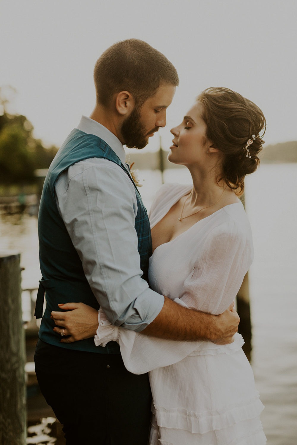 Couple embraces by a lake at sunset wedding 