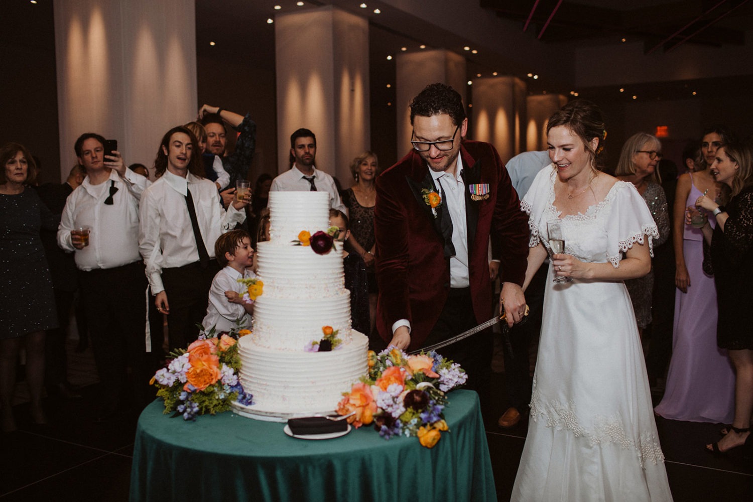 Couple cuts wedding cake with Marine sword arch