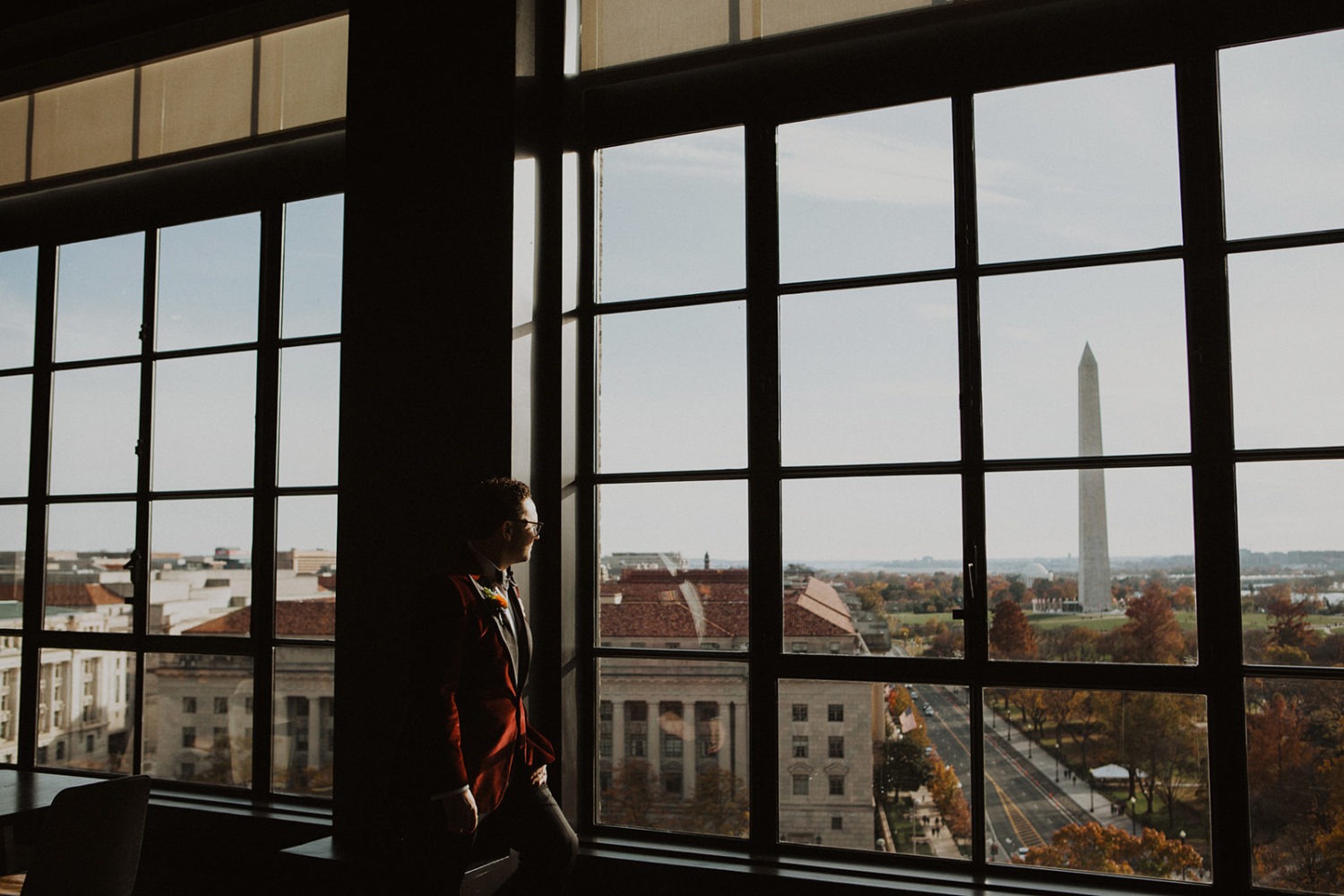 Groom looks outside window onto Washington Monument
