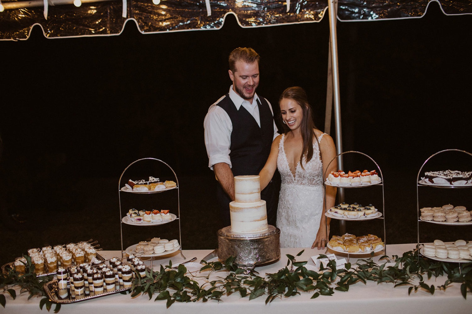 Couple cuts cakes at backyard wedding reception