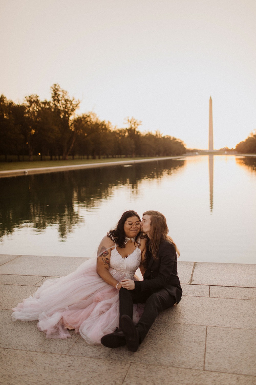 Couple sits by Reflecting Pool at sunset elopement