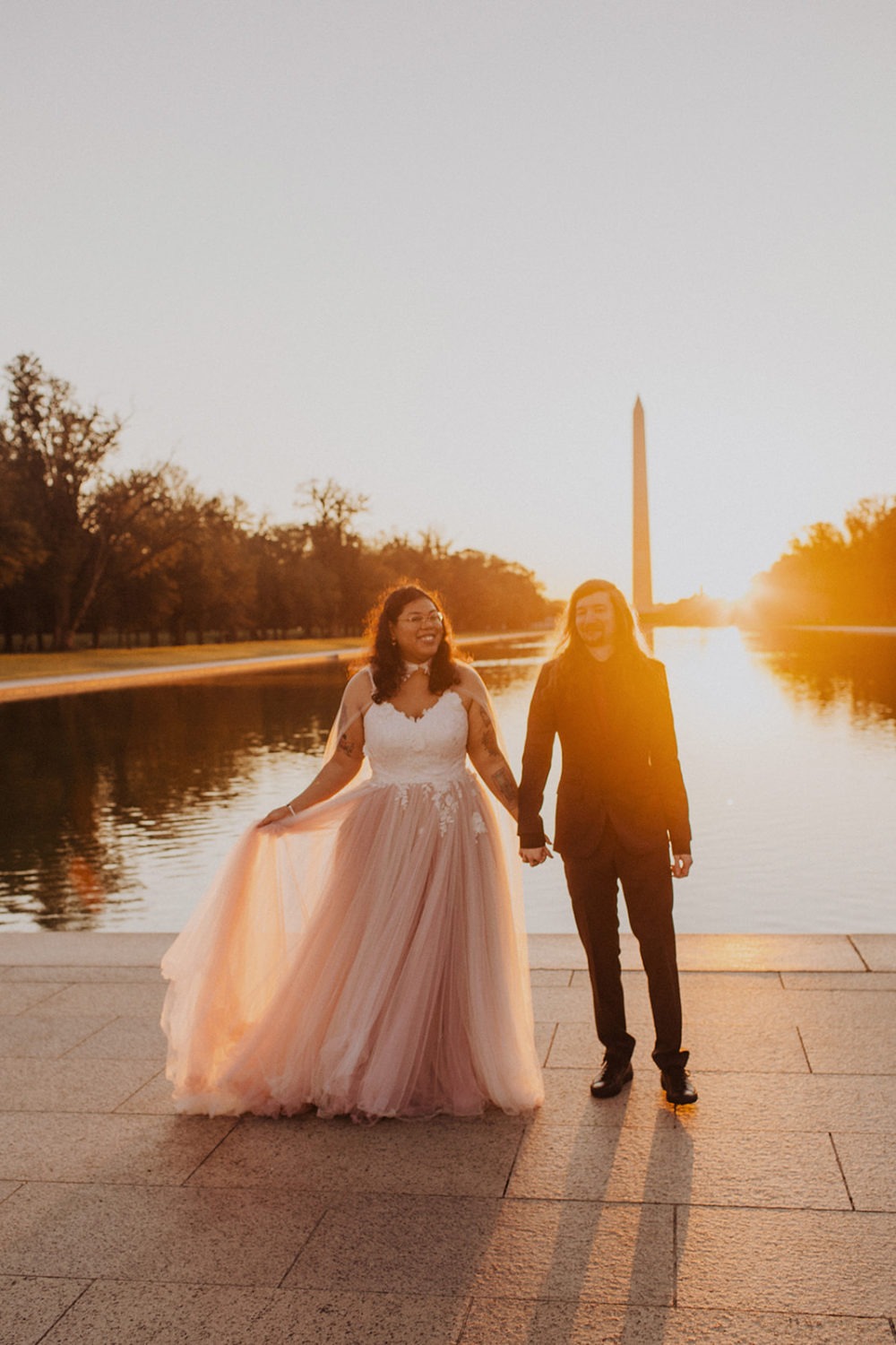 Couple holds hands at sunset beside Reflecting Pool 