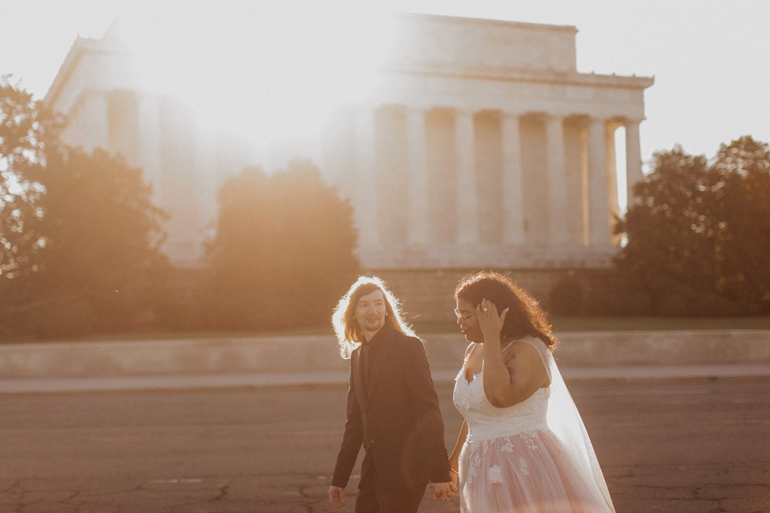 Couple walks holding hands beside Lincoln Memorial at sunset