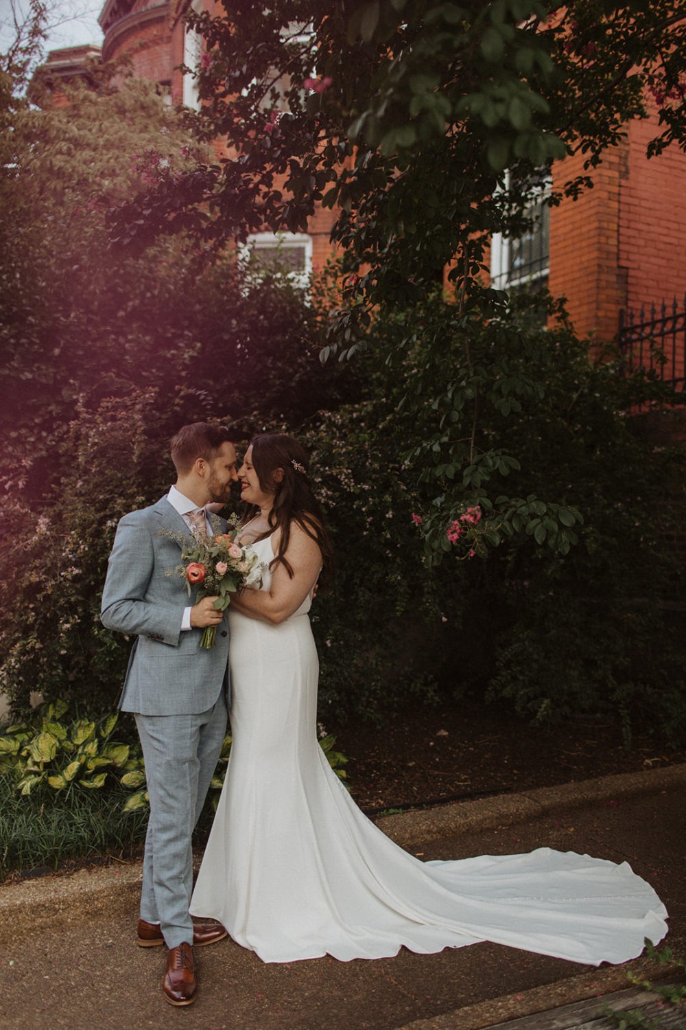 Couple embraces holding wedding bouquet on DC street 