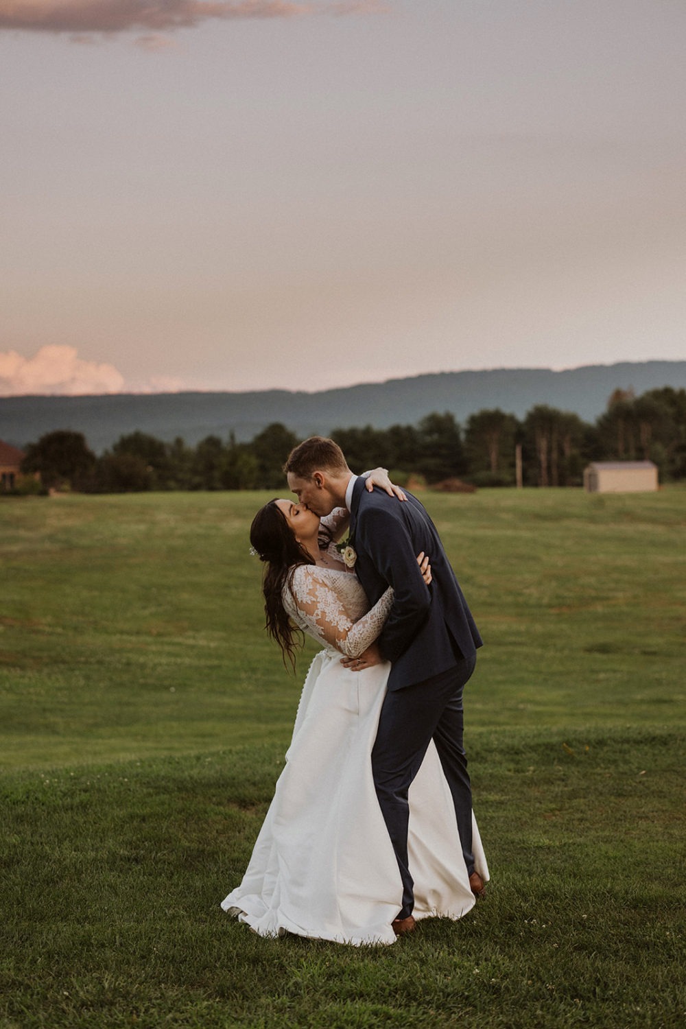 couple kisses on farm sunset wedding
