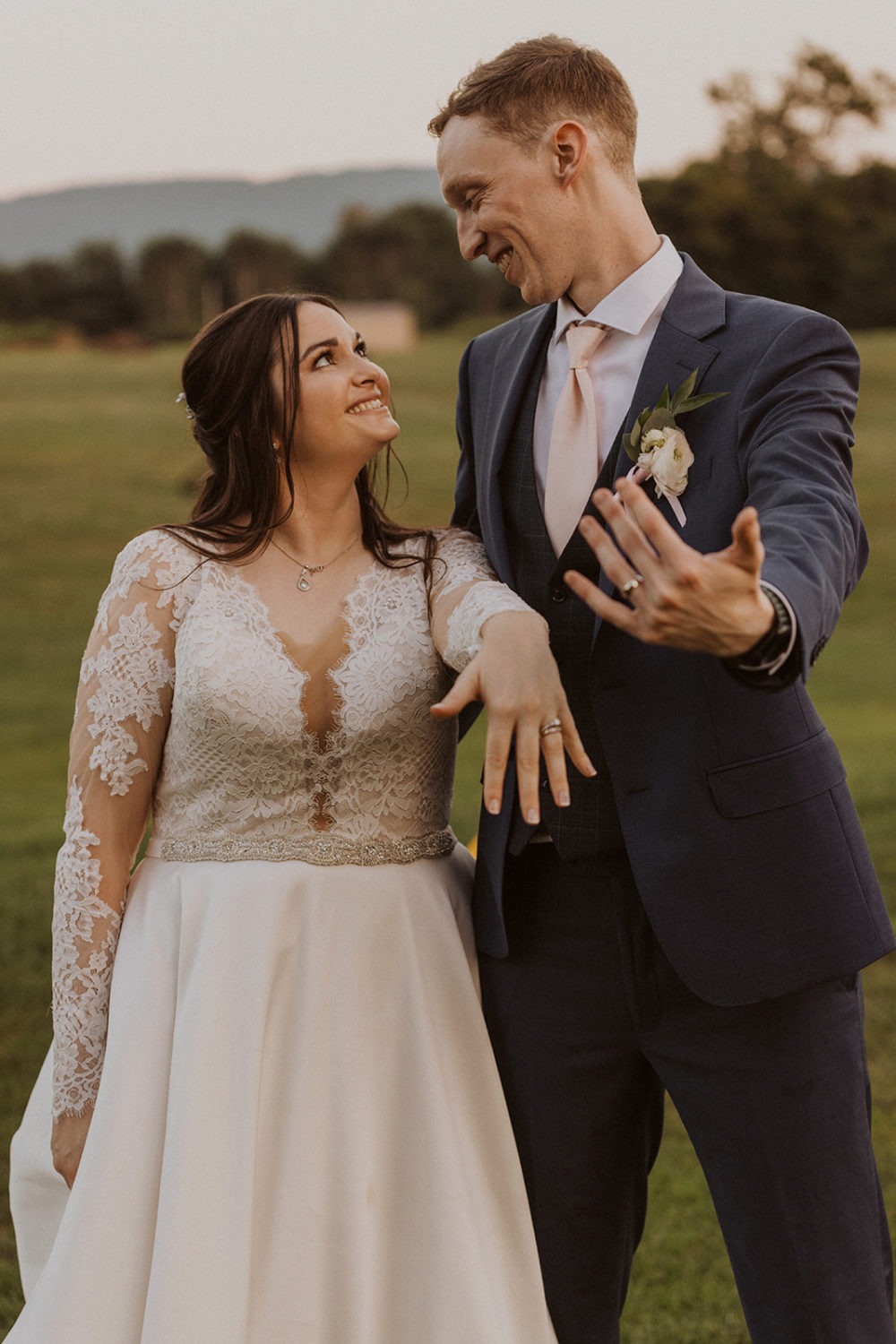 couple shows rings on hands at farm sunset wedding
