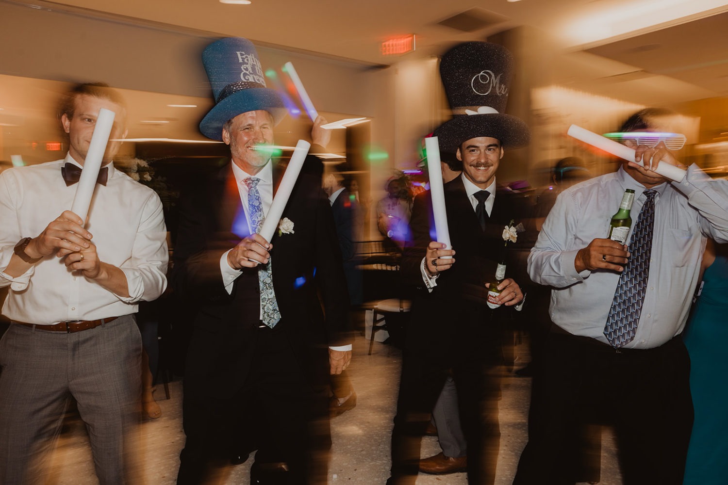 guests dance with glow sticks and hats at wedding reception dance party