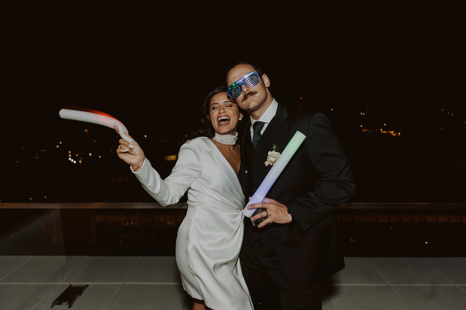 couple dances with glow sticks and sunglasses at wedding reception dance party