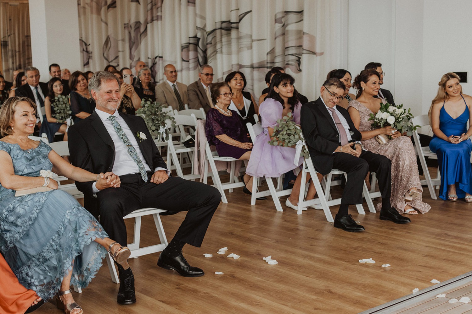 guests sit in white chairs at small and intimate wedding