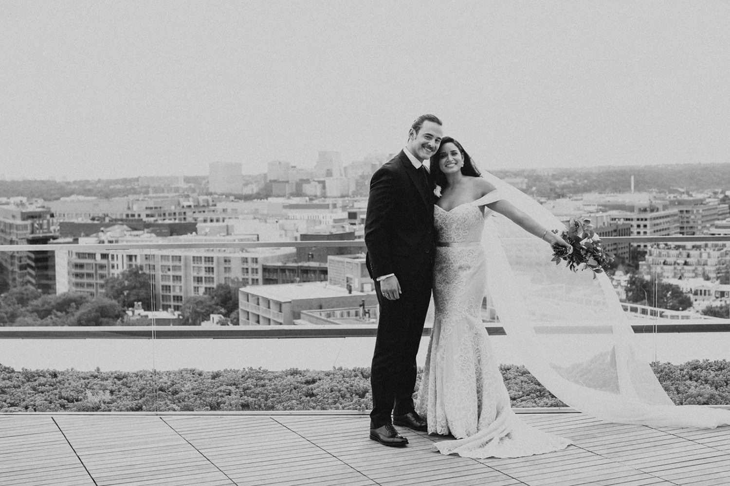 couple embraces on DC rooftop with veil flowing in wind