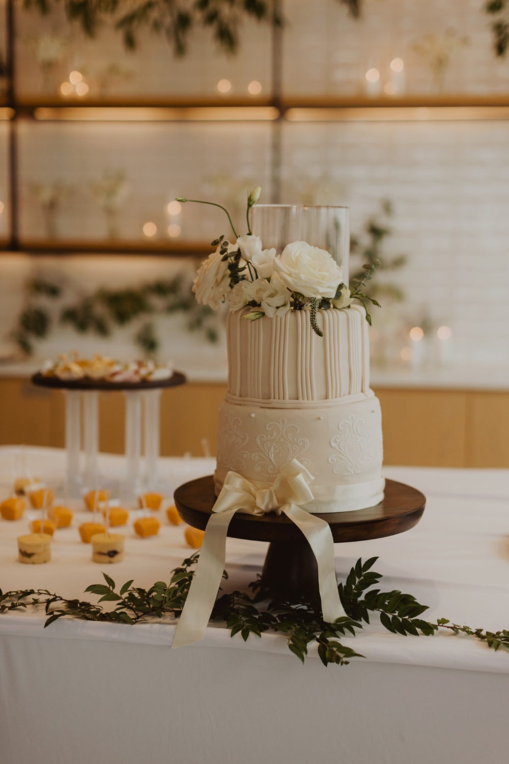 white wedding cake with white florals and bow at rooftop wedding venue