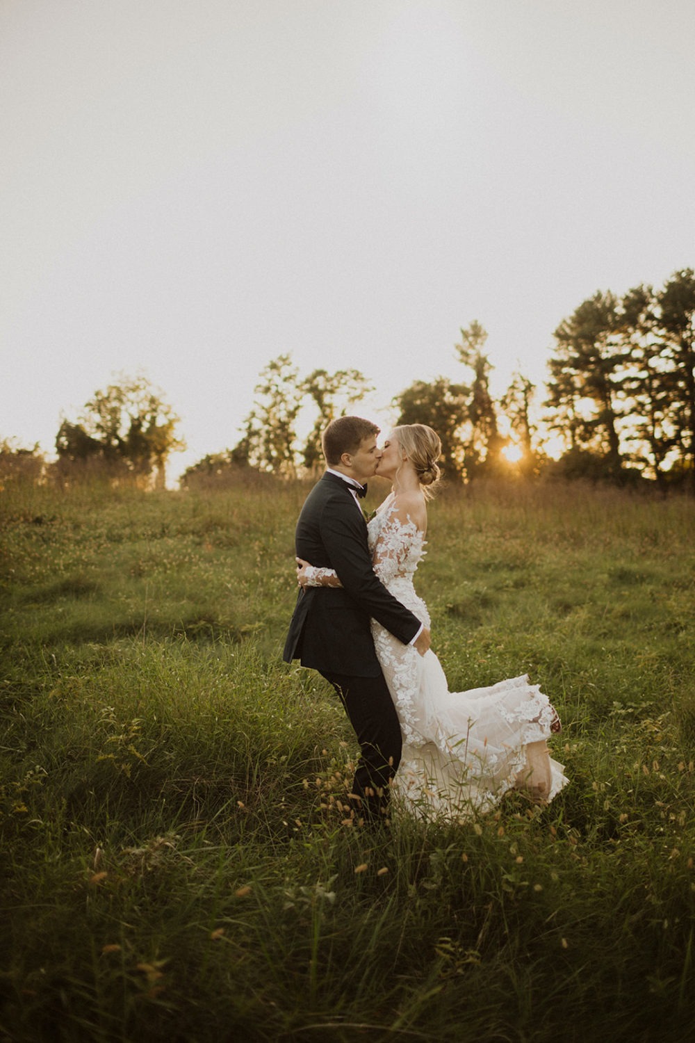 couple kisses in field of grass at sunset at Airlie Warrenton, VA wedding venue 