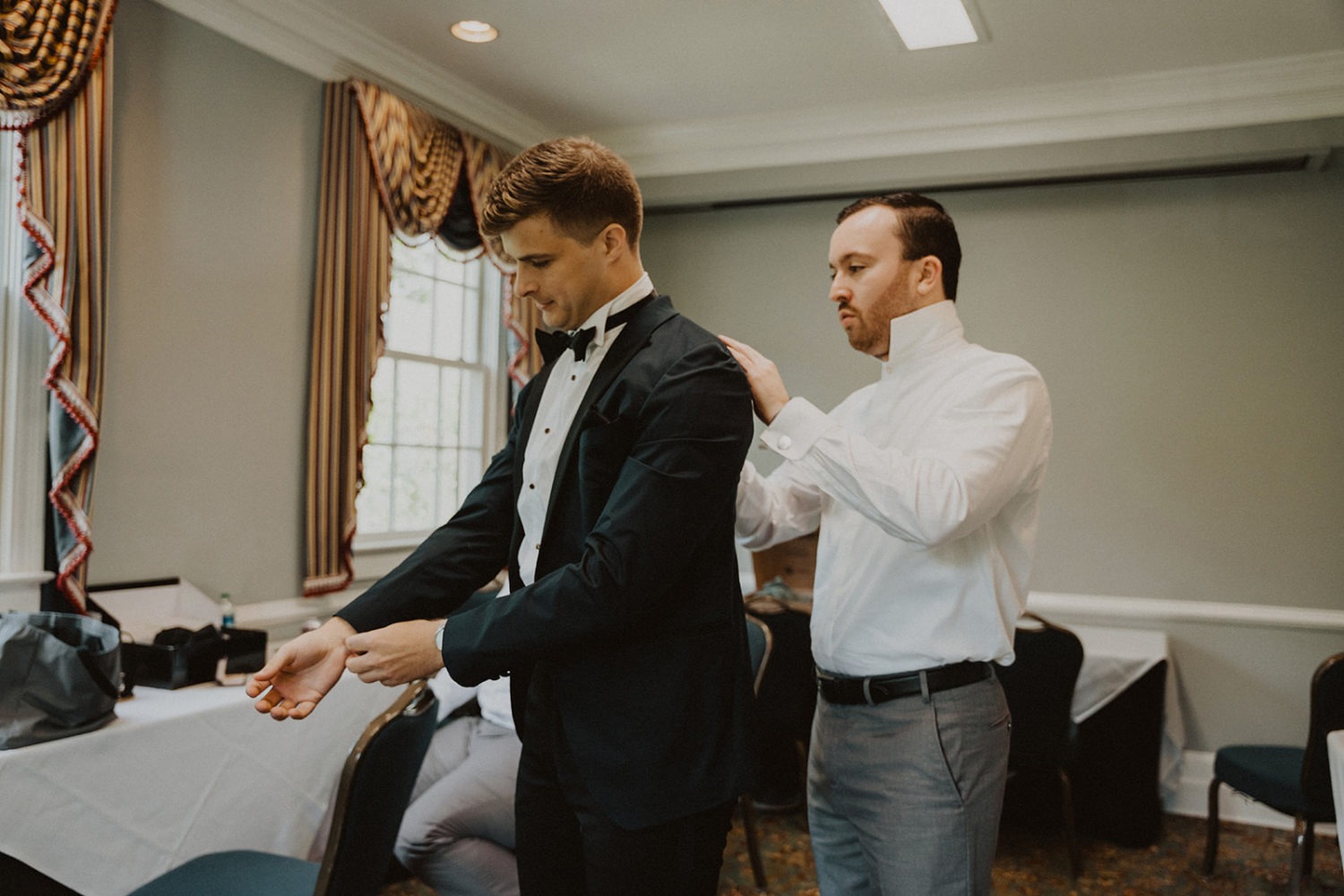 groom gets ready putting on tux jacket