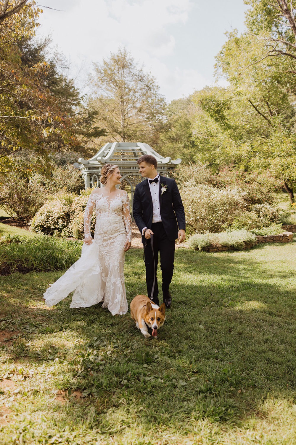 couple walks together with dog at garden wedding 