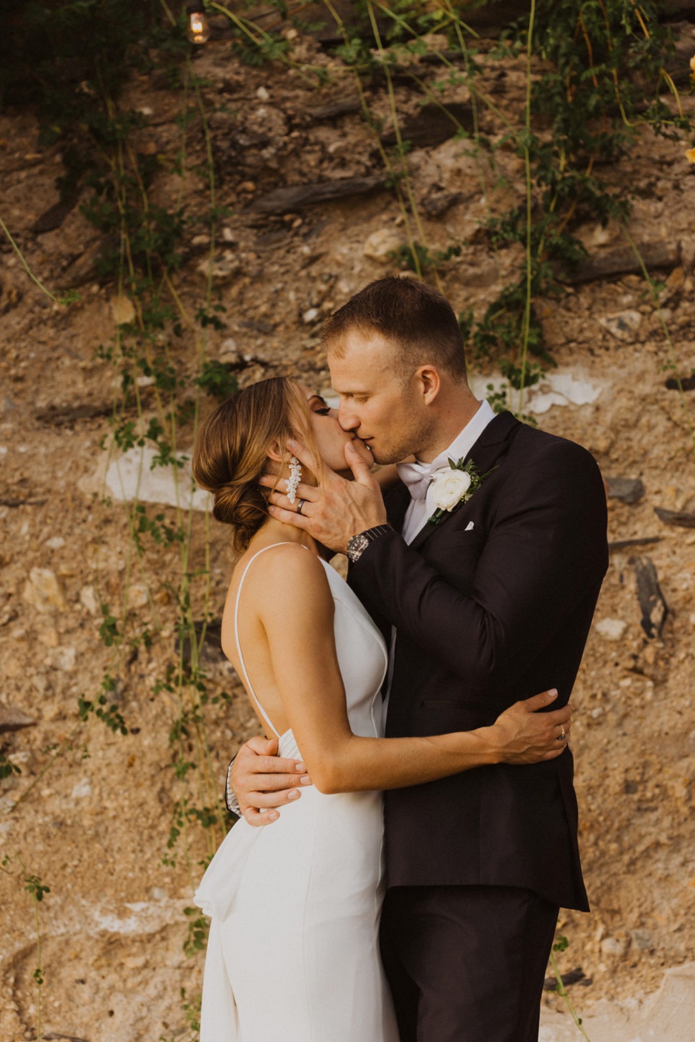 couple kisses in front of stone barn ruins
