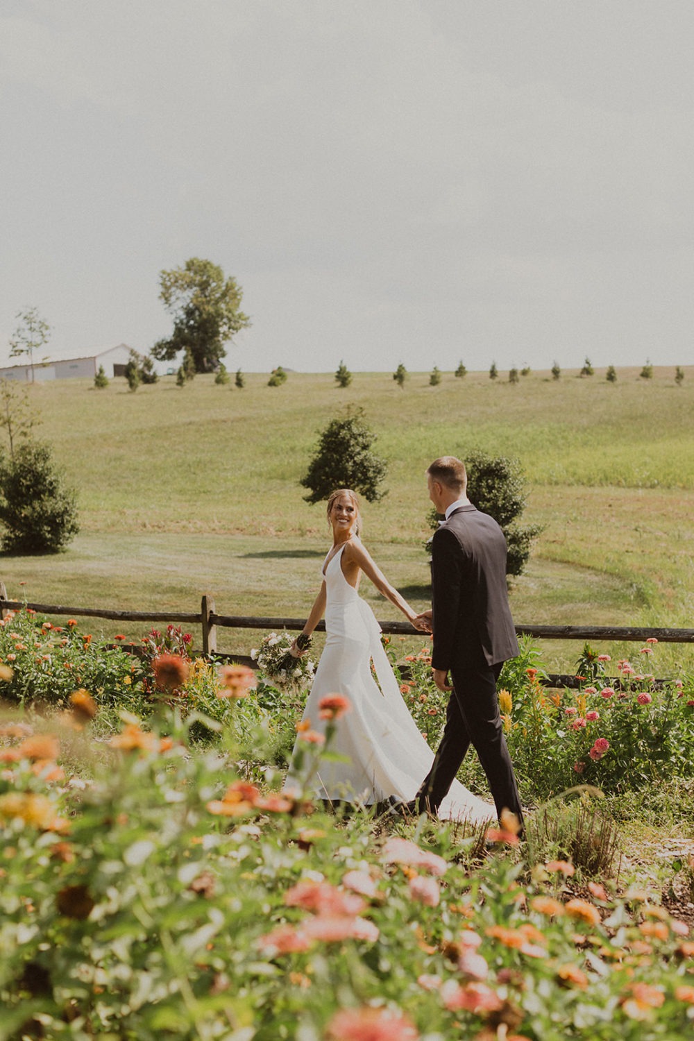 Couple walks through flower field at Glen Ellen Farms wedding