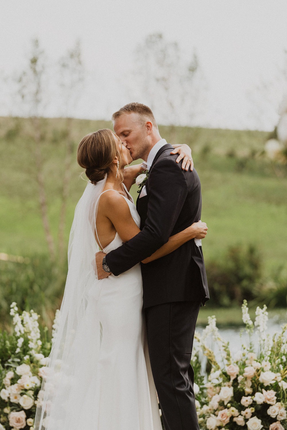 Couple kisses in wildflower garden at Glen Ellen Farm wedding