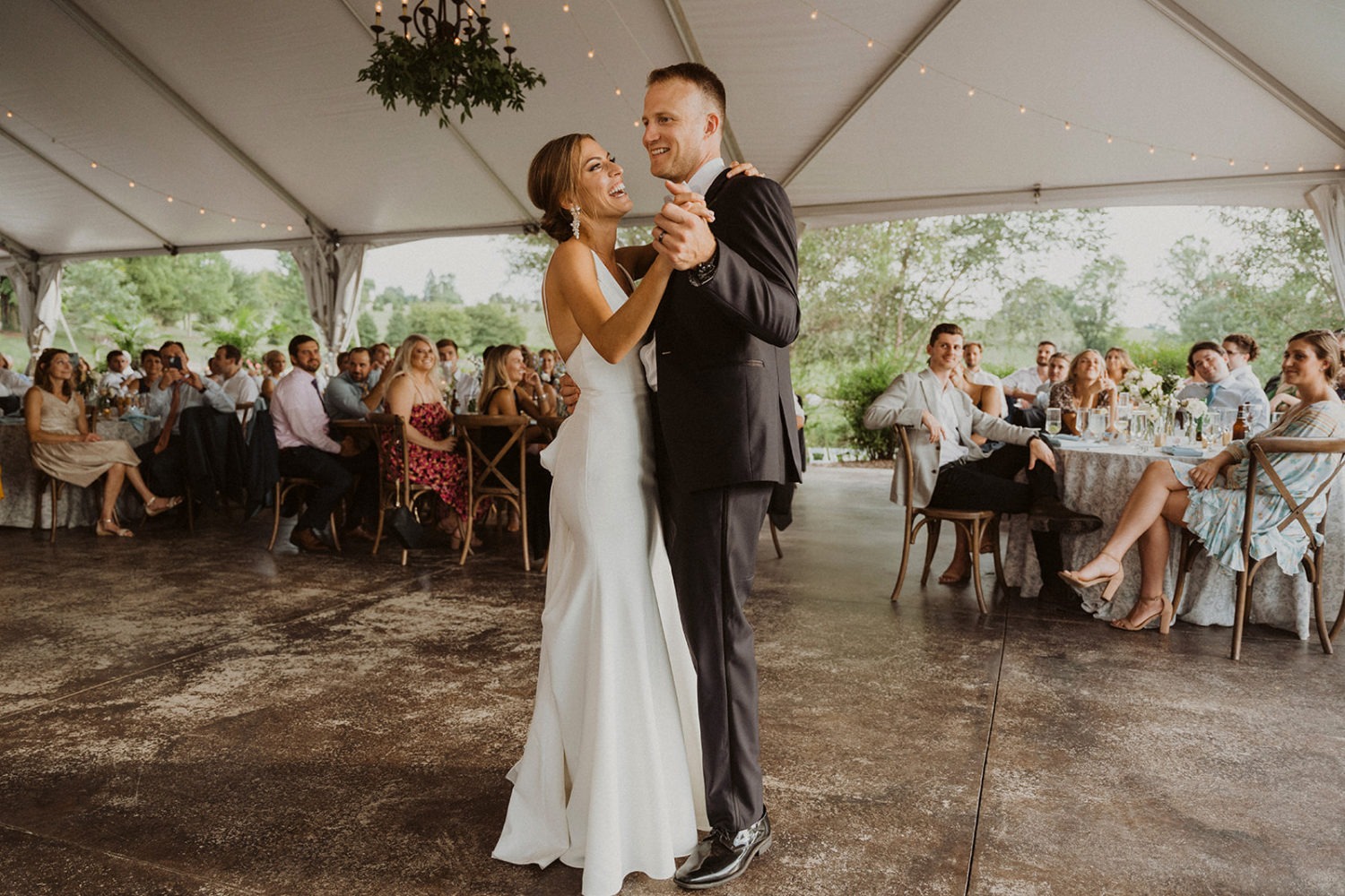 couple has first dance under wedding reception tent