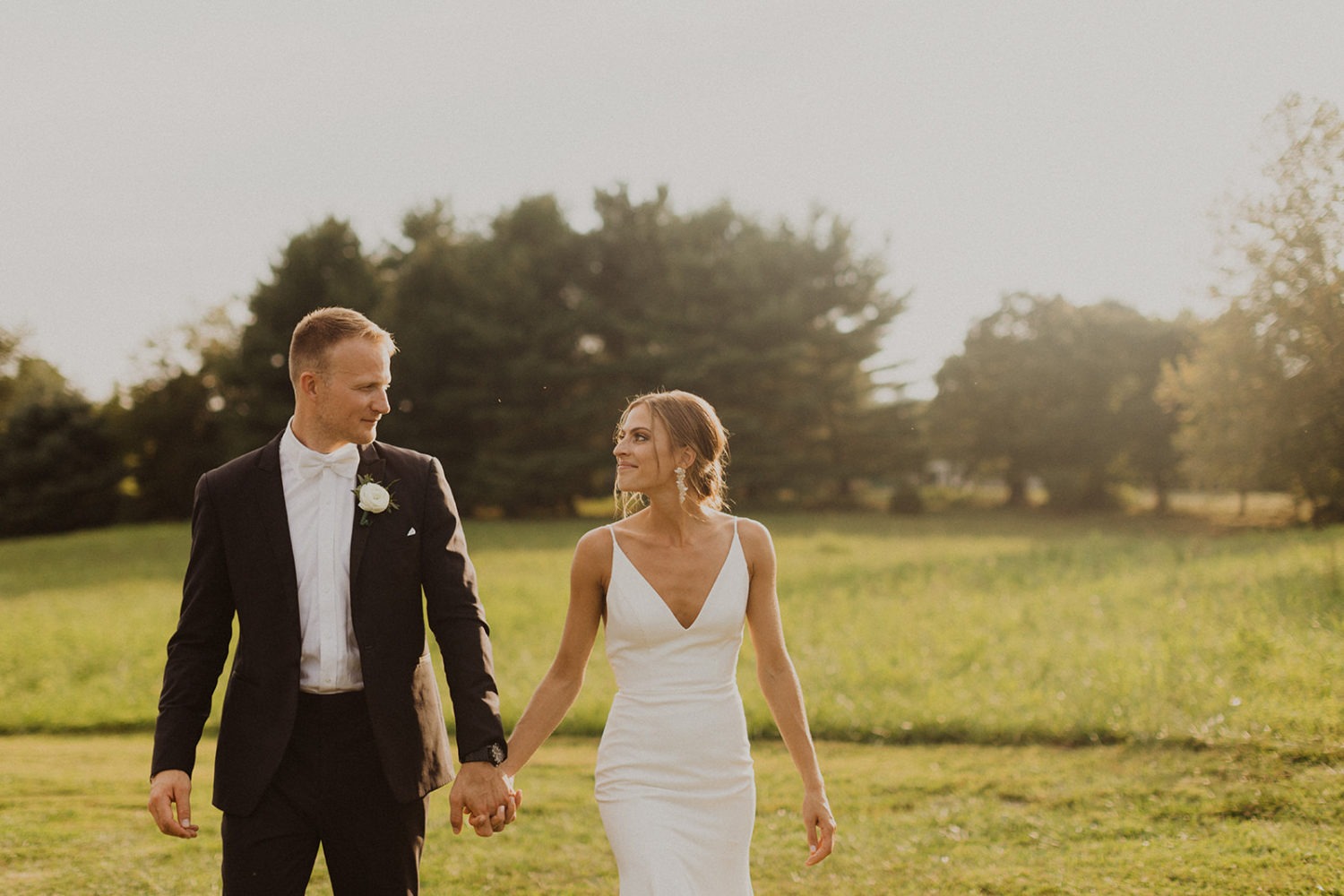 Couple walks through sunset field at Glen Ellen Farms wedding