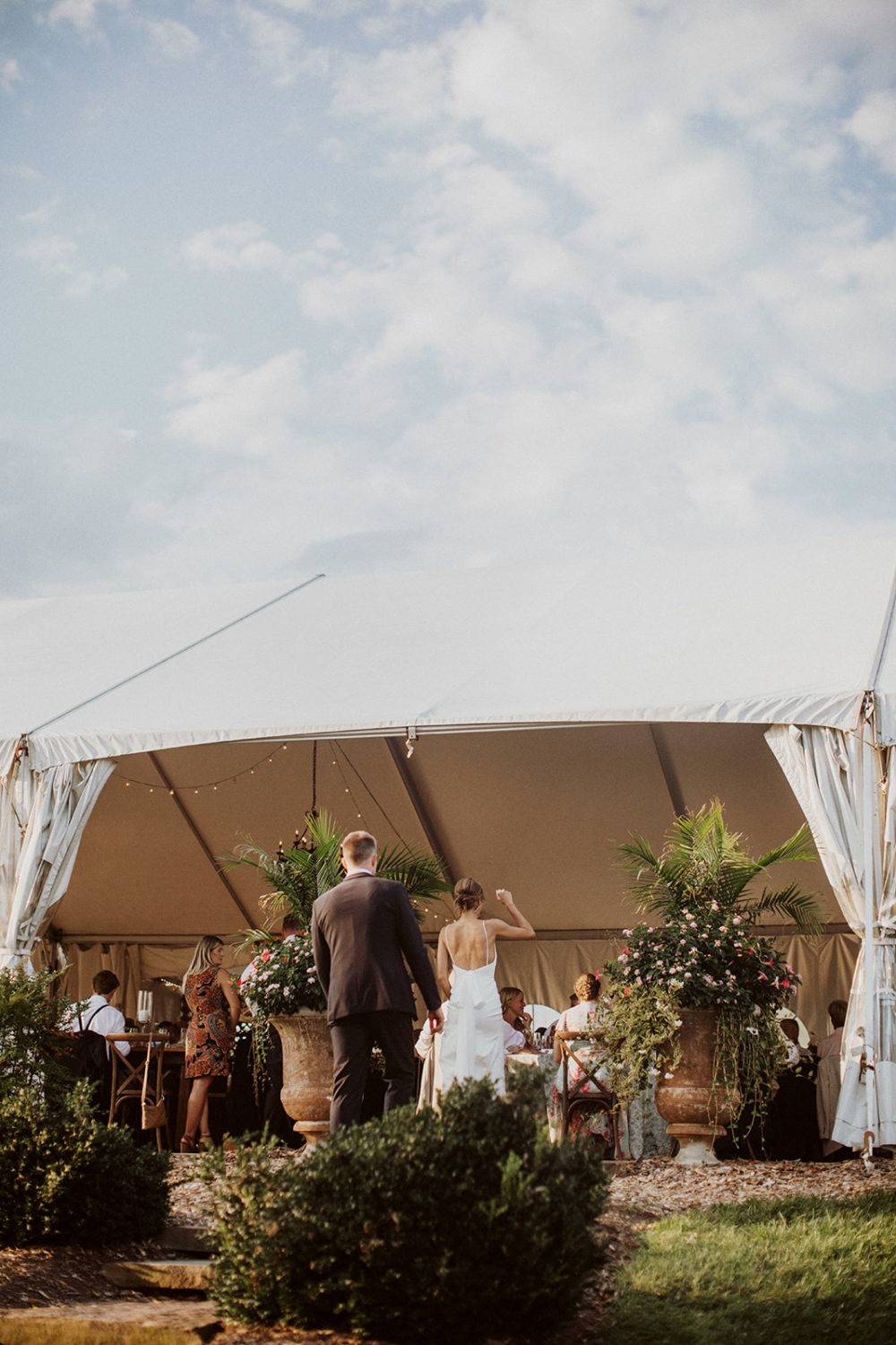 couple cheers standing outside of wedding reception tent