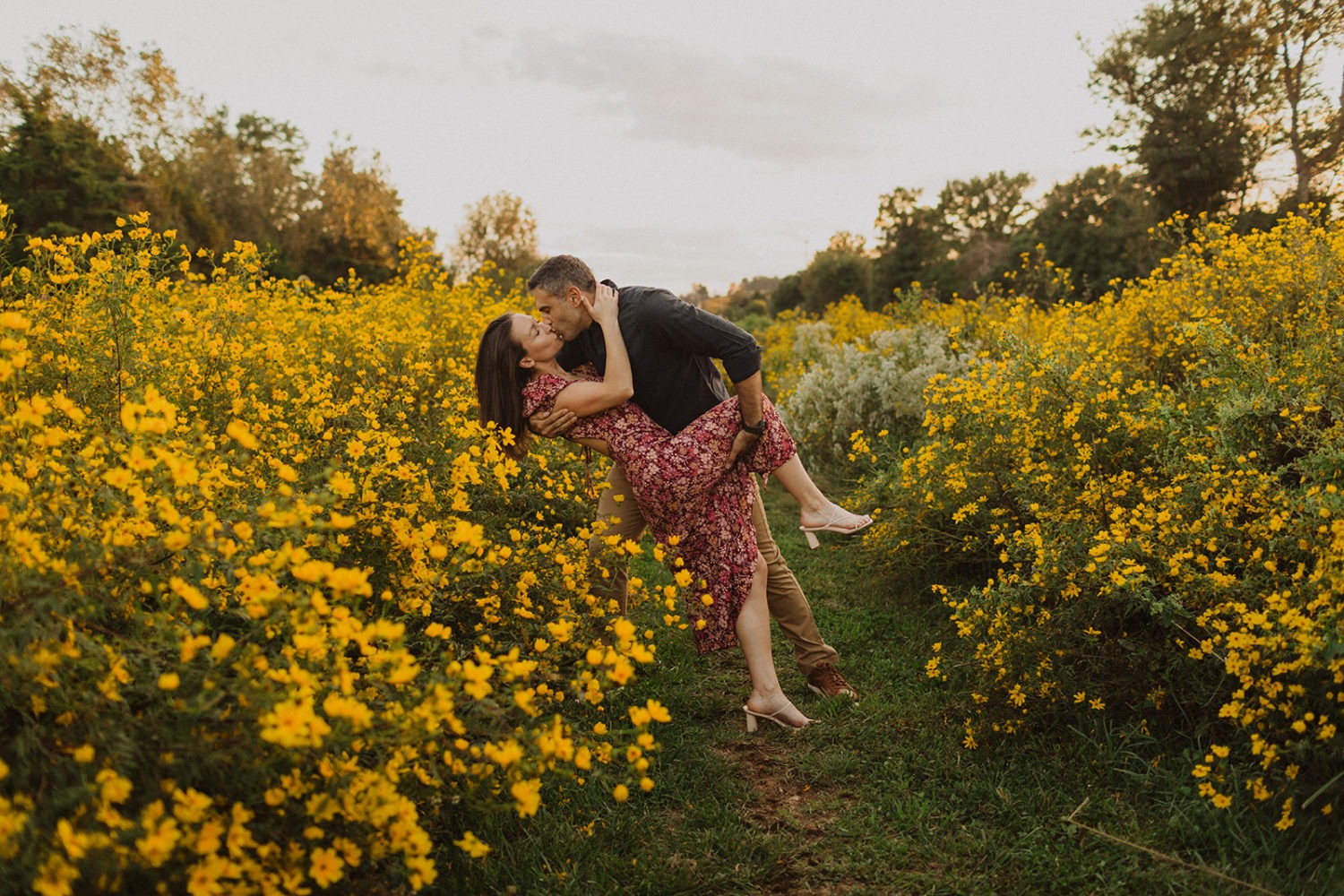 couple kisses in wildflower field at engagement session