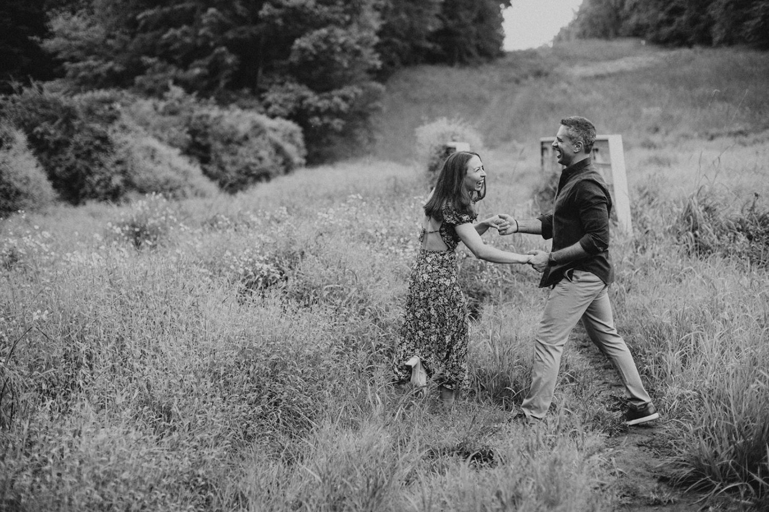 couple holds hands at wildflower field engagement session