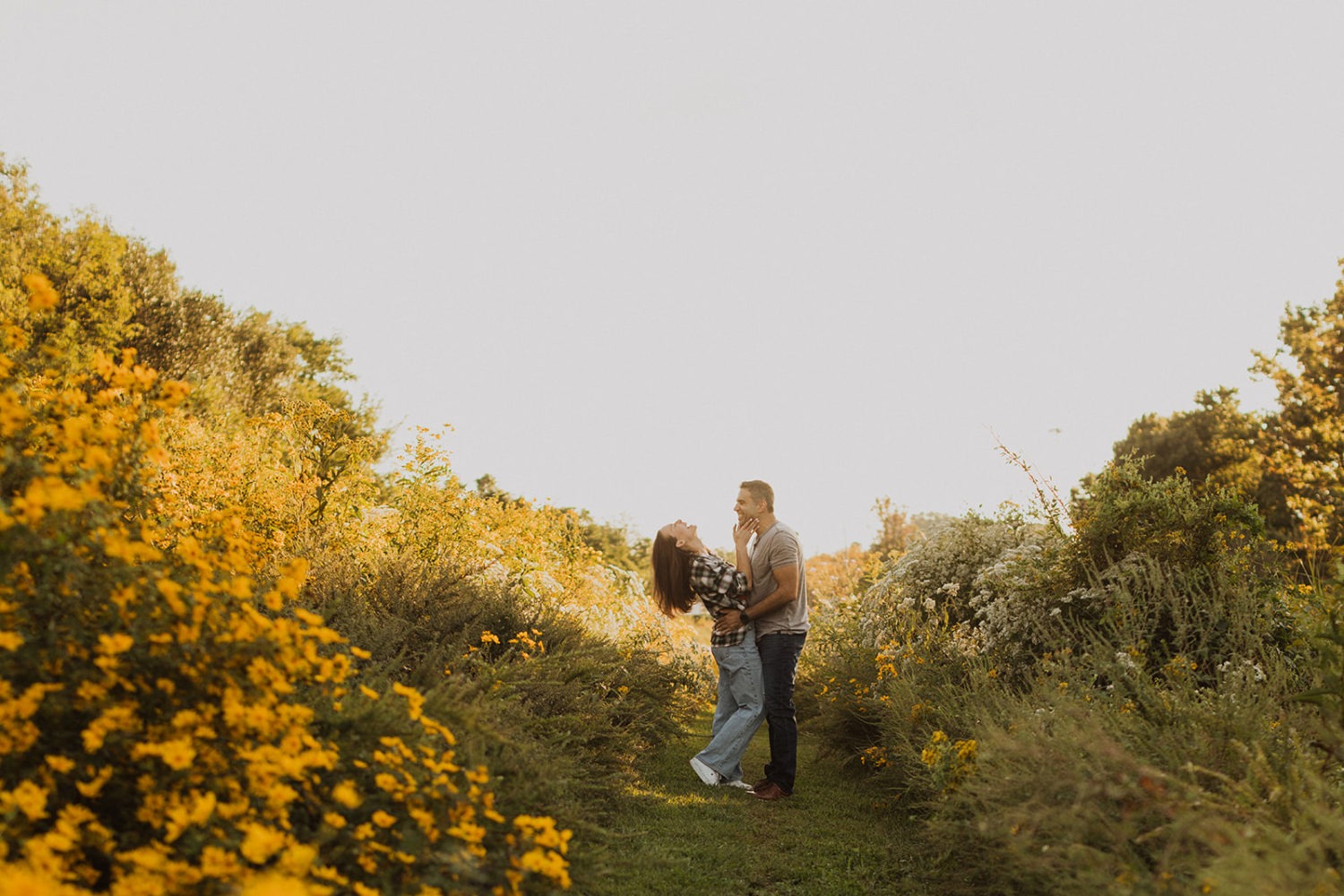 couple laughs in wildflower field at sunset engagement session