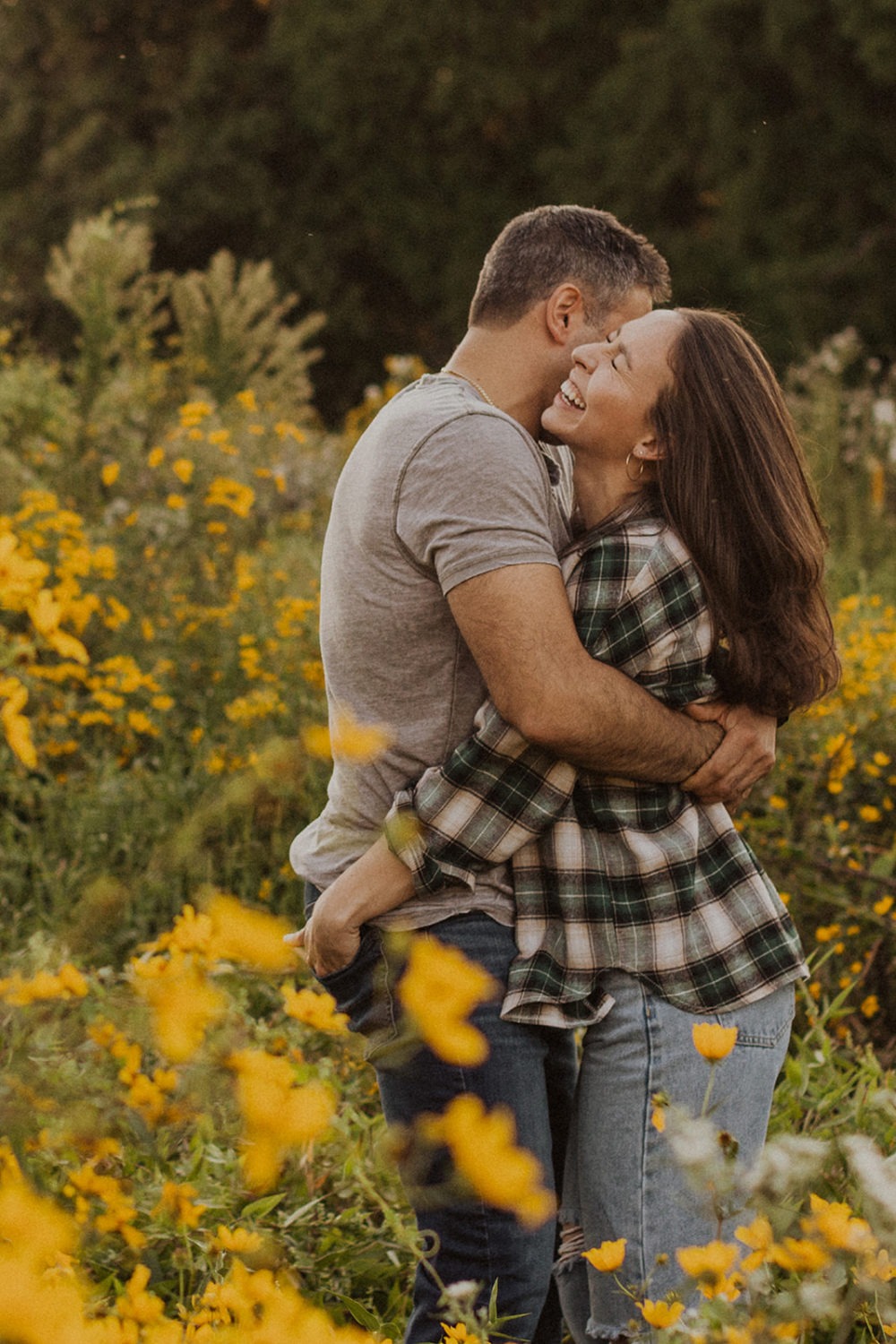 couple embraces in wildflower field at sunset engagement session