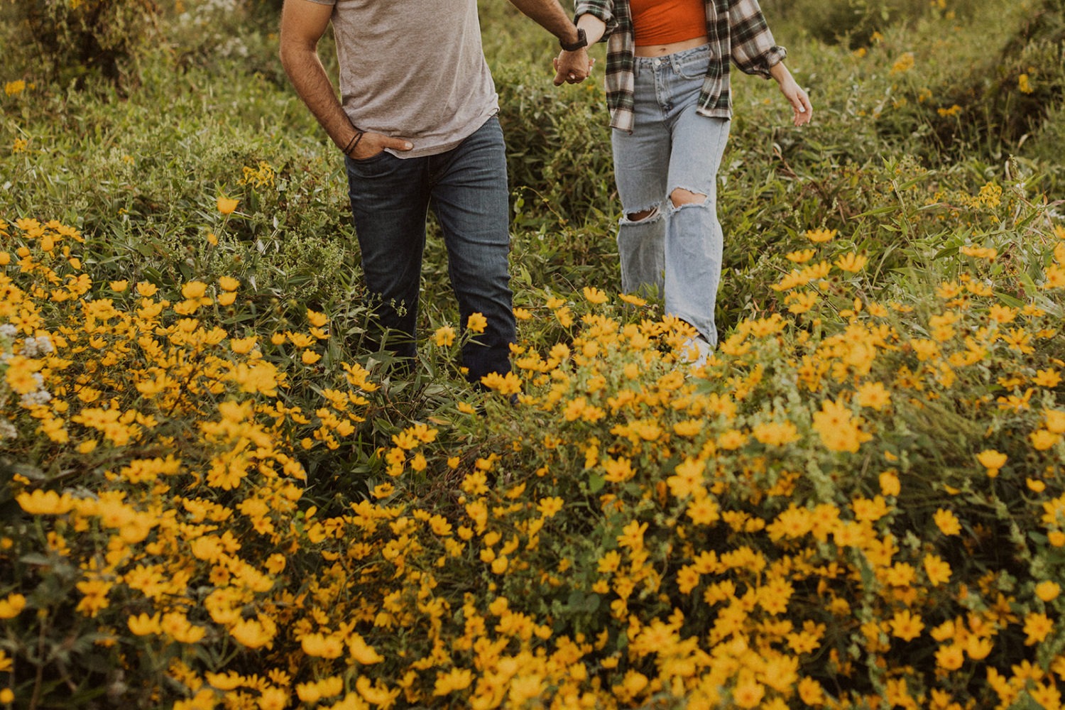 couple walks through wildflower field holding hands