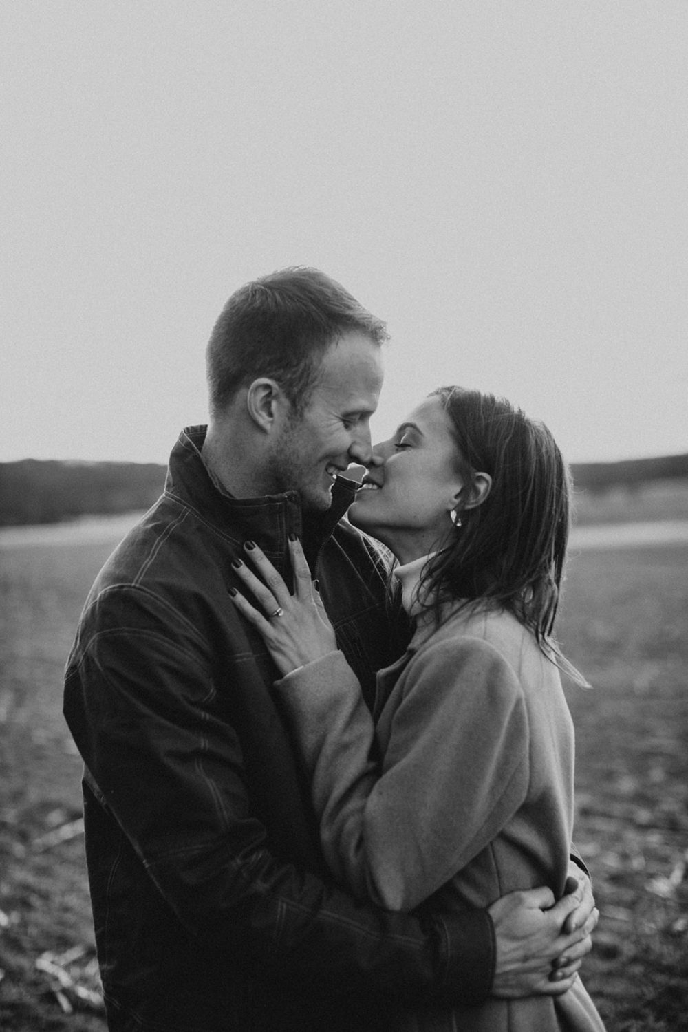 couple almost kisses standing in field 