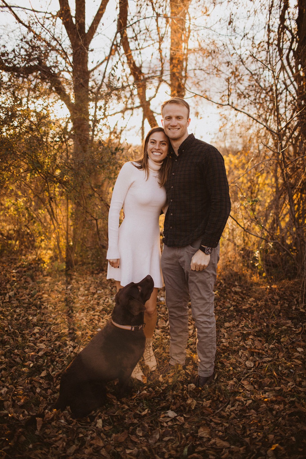 couple embraces with dog at fall engagement photos session