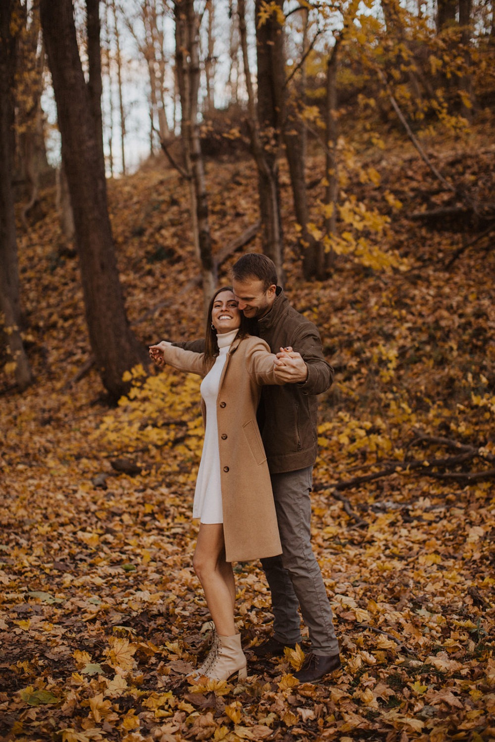 couple stands holding hands at fall engagement photos session