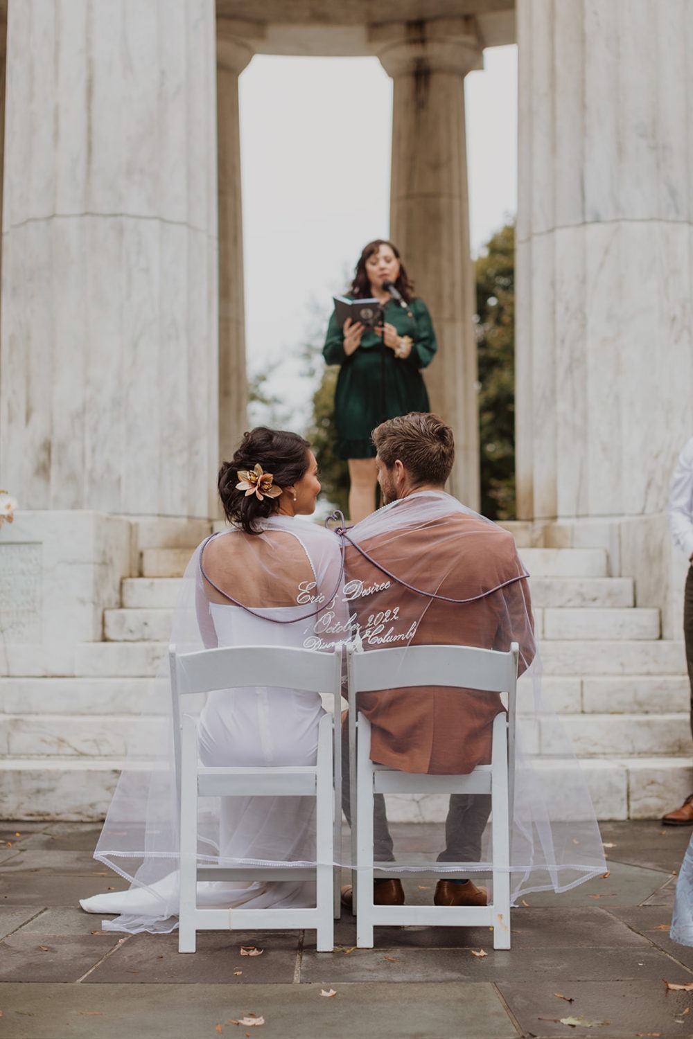 couple sits under ceremonial veil at DC War Memorial wedding ceremony
